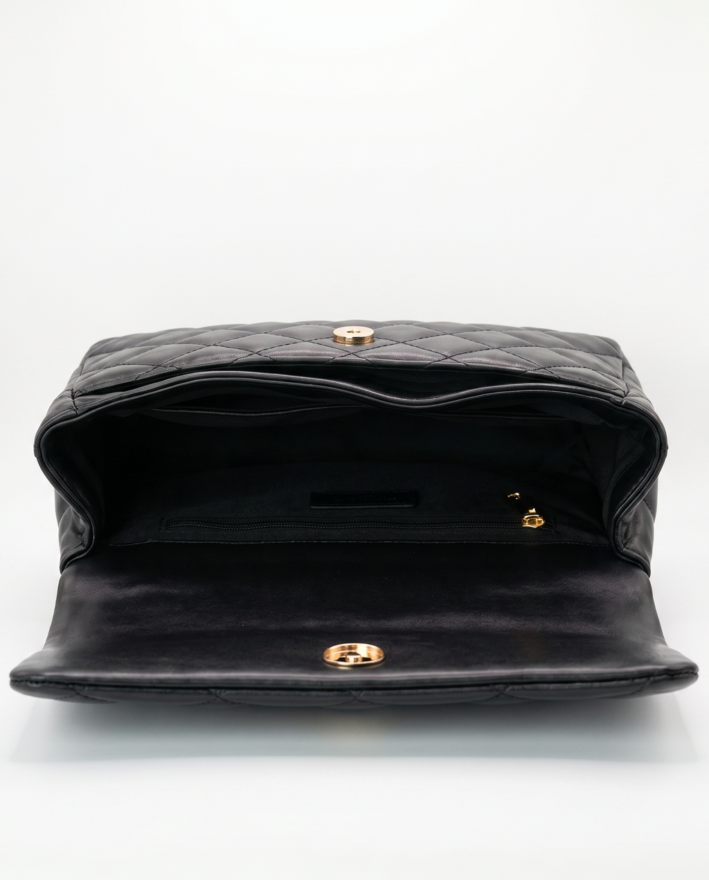 Interior of black quilted ChristAdorn handbag with magnetic closure and zip pocket compartment.
