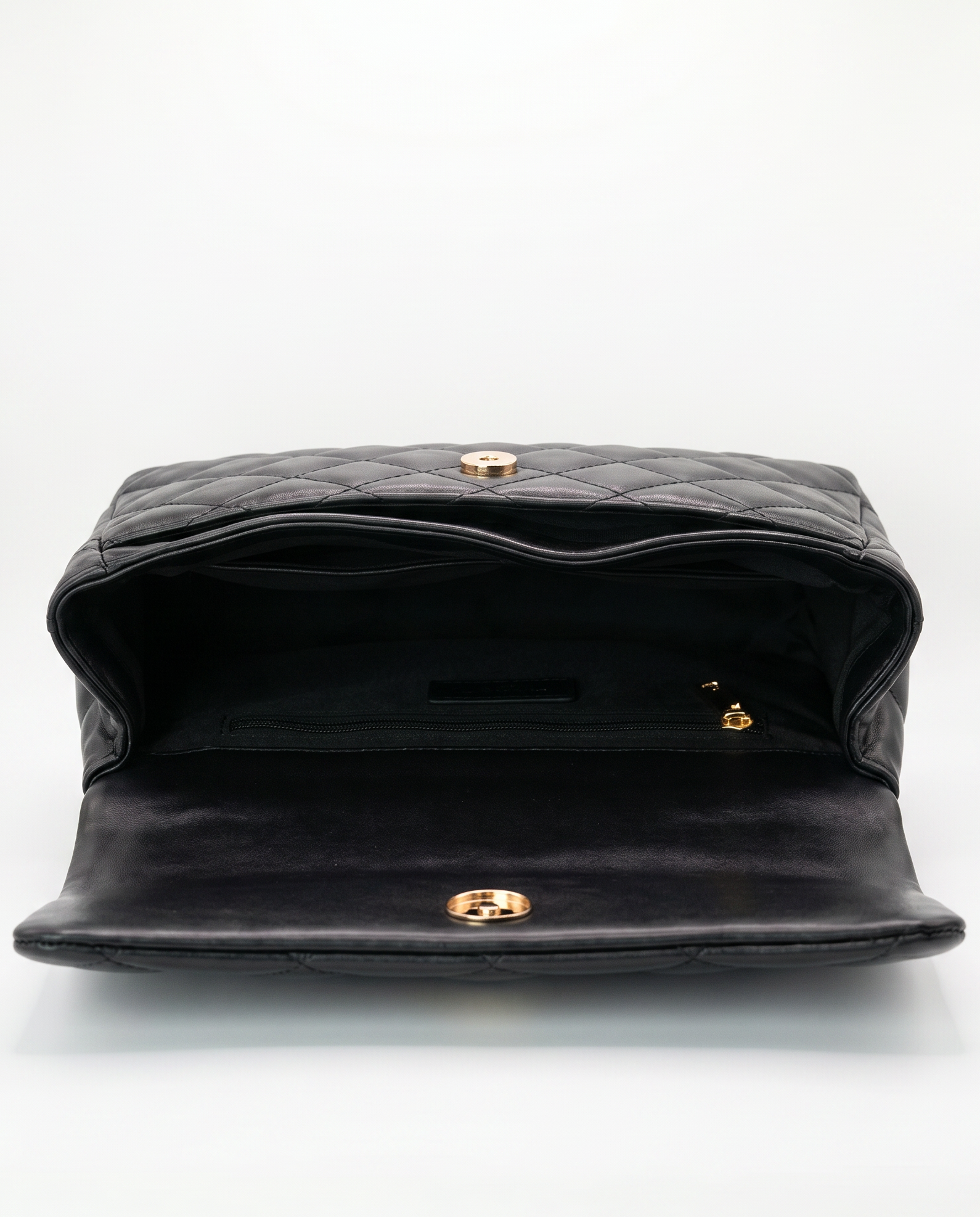 Interior of black quilted ChristAdorn handbag with magnetic closure and zip pocket compartment.
