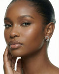 Close-up of model wearing silver pavé ChristAdorn logo stud earrings with a polished beauty look.